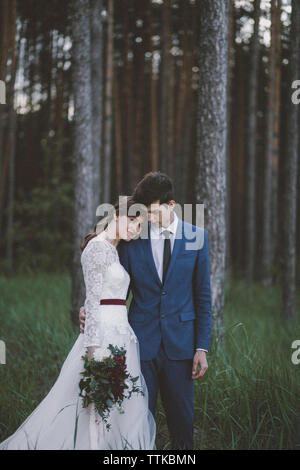 Mariée avec groom standing on grassy field in forest Banque D'Images