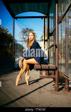 Ballerine femme dans la ville est assise sur un banc à l'arrêt de bus Banque D'Images