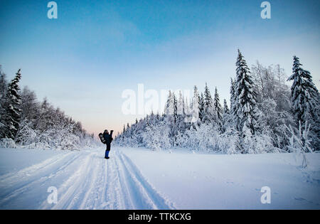 Randonneur debout sur le terrain couvert de neige contre le ciel Banque D'Images