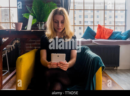 Woman using tablet computer on fauteuil à la maison Banque D'Images