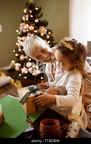 Heureux grand-mère à la petite fille au cadeau d'emballage à table Banque D'Images