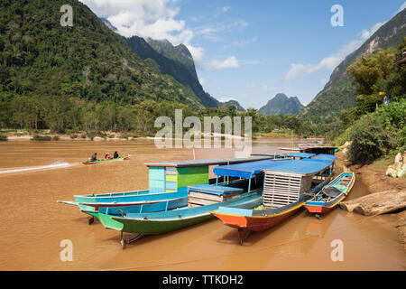 Bateaux d'excursion bleus amarrés sur le fleuve Nam ou à Muang Ngoi Neua en regardant vers le nord, district de Muang Ngoi, province de Luang Prabang, nord du Laos, Laos, Asie du Sud-est Banque D'Images