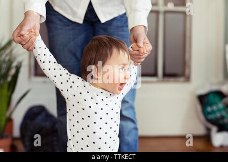 Midsection of woman's hands holding sa petite-fille à la maison Banque D'Images