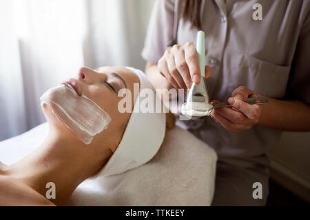 Au milieu de l'application de masque facial thérapeute on woman Banque D'Images