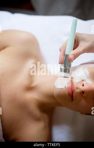 Vue de dessus de la crème appliquée sur le visage de femme à spa Banque D'Images