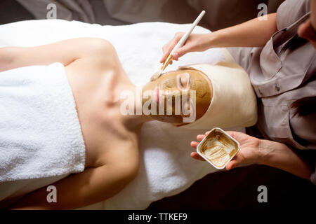 Vue de dessus de female therapist appliquant le masque facial sur visage de femme à spa Banque D'Images
