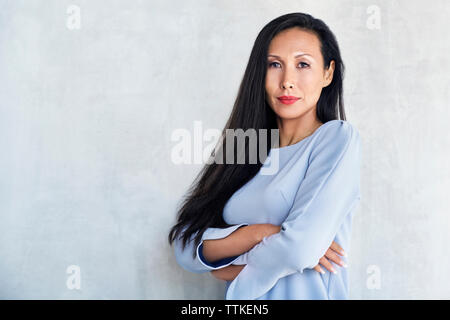 Portrait of businesswoman standing arms crossed contre mur Banque D'Images