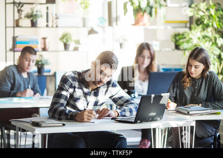 Les élèves assis à table pendant la leçon en classe Banque D'Images