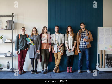 Portrait of friends standing against wall in classroom Banque D'Images