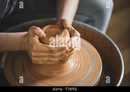 Les mains de potter femelle recadrée de la pâte à modeler en atelier Banque D'Images