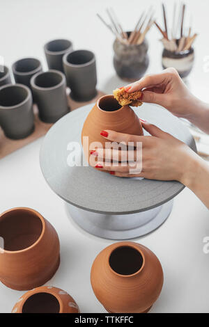 Les mains coupées de potter faire la céramique de table en atelier Banque D'Images