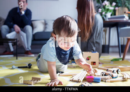 Boy Playing with toy train tandis que les parents en arrière-plan Banque D'Images