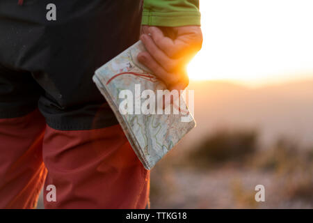 Close up of senior male hands holding une carte sur le dessus de la montagne au coucher du soleil Banque D'Images