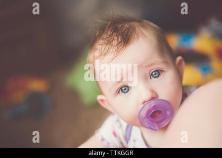 Close-up portrait of cute baby girl sucking pacifier à la maison Banque D'Images