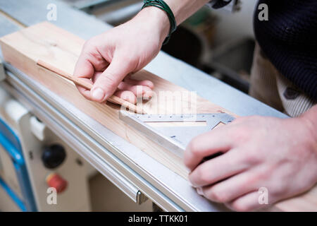 Les mains coupées de carpenter measuring planches en bois en atelier Banque D'Images