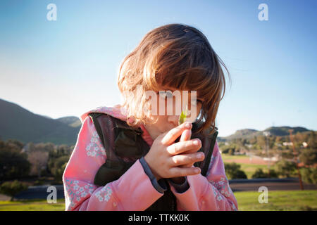 Close-up of Girl with hands clasped sur terrain contre ciel clair Banque D'Images