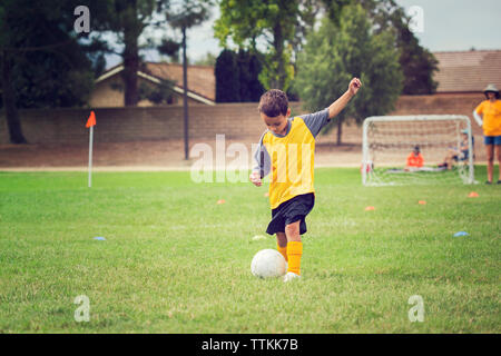 Garçon jouant au football sur terrain herbeux Banque D'Images