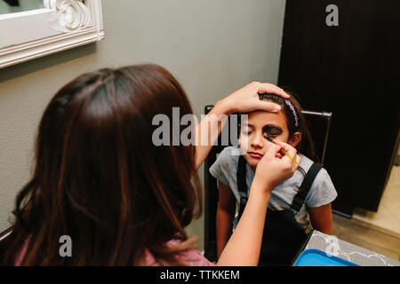 Woman applying make-up sur le visage de fille à la maison Banque D'Images