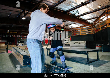 Aide à l'instructeur de skateboard grind étudiant une plate-forme Banque D'Images