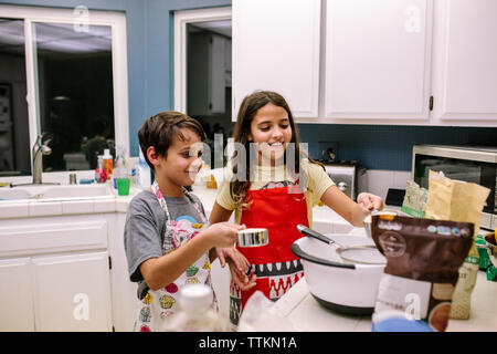 Frère et soeur sourire pendant la cuisson dans la cuisine la nuit Banque D'Images