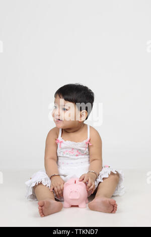 Baby girl playing with a piggy bank Stock Photo