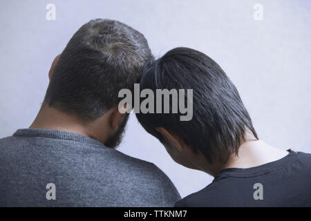 Vue arrière du couple gay par mur blanc à la maison Banque D'Images