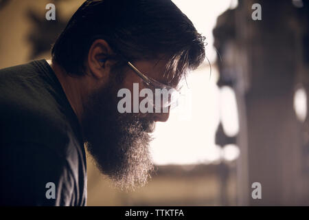 Close-up of blacksmith portant des lunettes travaillant en atelier Banque D'Images