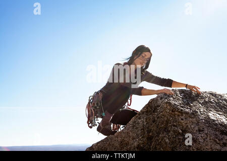 Femme escalade contre le ciel aux beaux jours Banque D'Images