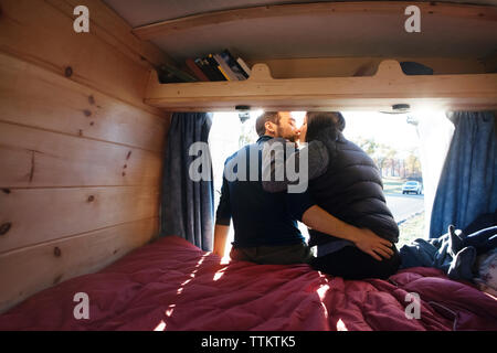 Vue arrière du couple tout en restant assis sur le lit dans le camping-car Banque D'Images