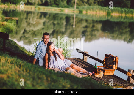 Happy couple relaxing on pier by lake at park Banque D'Images
