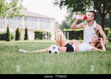 Jeune couple en appui sur le terrain de soccer au parc Banque D'Images