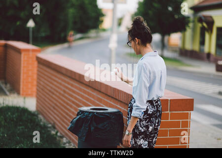 Woman throwing garbage in container Banque D'Images