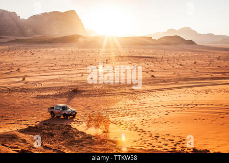 Un touriste Mitsubishi jeep au coucher du soleil dans le désert jordanien à Wadi Rum ou la vallée de la Lune. Banque D'Images