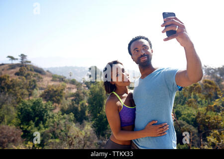 Couple qui par selfies tél. mobile sur terrain Banque D'Images