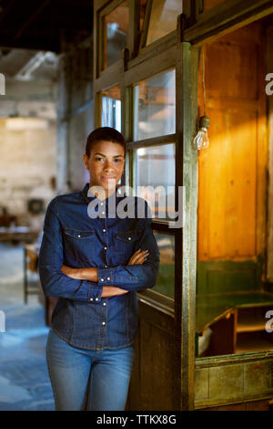 Certain young woman standing with arms crossed by window Banque D'Images