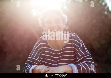 Portrait of woman smiling while standing on sunny day Banque D'Images