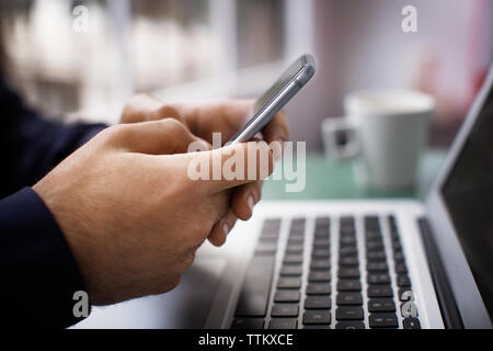 Close-up of woman's hands using smart phone in creative office plus Banque D'Images