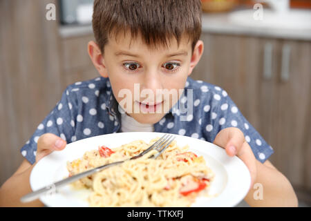 Cute boy eating spaghetti sur la cuisine Banque D'Images