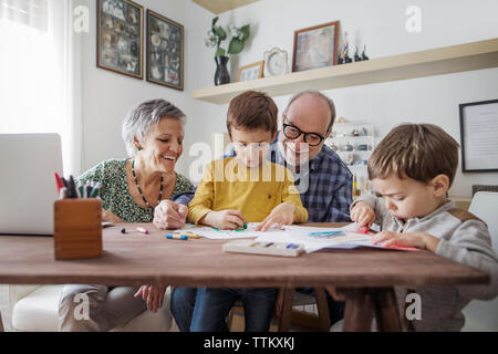 Heureux grands-parents à petits-fils à faire des dessins à la maison Banque D'Images
