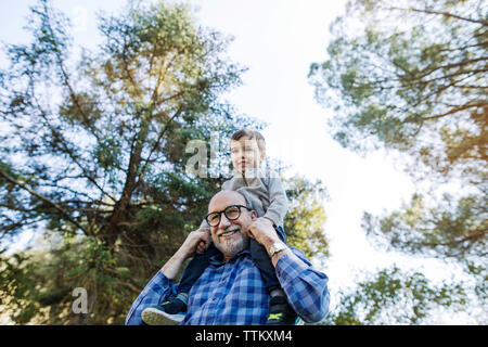 Low angle view of happy senior man carrying grandson sur les épaules contre le ciel Banque D'Images