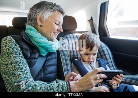 Happy senior woman using smart phone avec petit-fils dans... Banque D'Images