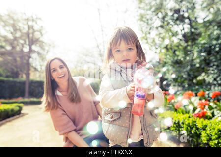 Happy woman holding bubble gun in park Banque D'Images