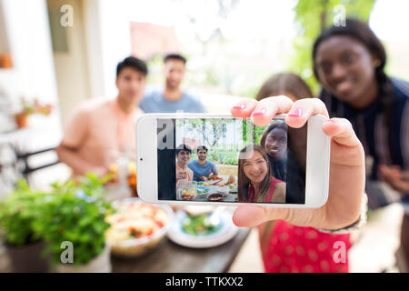 Multi-ethnic friends at outdoor table du déjeuner selfies Banque D'Images