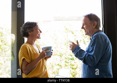 Vue latérale du senior couple having coffee par fenêtre à la maison Banque D'Images