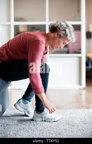 Vue latérale d'attacher les lacets femme mature à la maison Banque D'Images