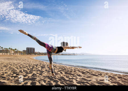 Yoga déterminé dans Warrior 3 poser sur plage Banque D'Images