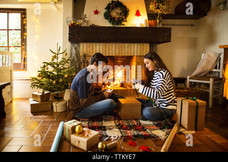 Mise sous film rétractable des boîtes cadeau couple sur marbre par cheminée à la maison Banque D'Images