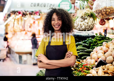 Portrait of owner with arms crossed standing at market stall Banque D'Images