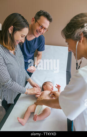 Heureux parents regardant doctor examining baby boy in medical clinic Banque D'Images