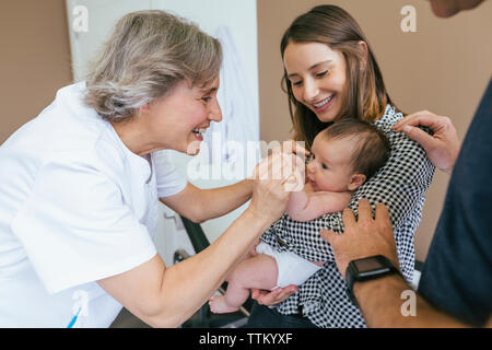 Smiling mother looking at médecin jouant avec baby boy in examination room Banque D'Images